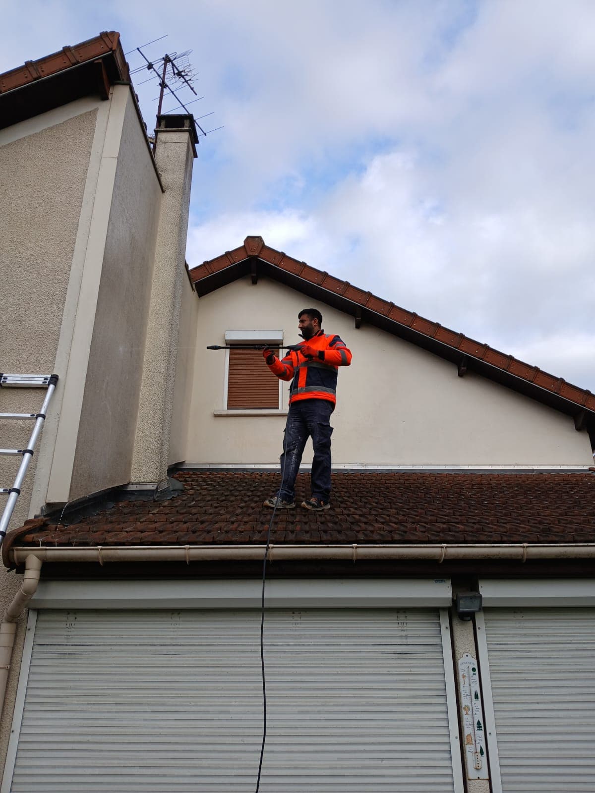 Ouvrier nettoyant la façade sur la toiture