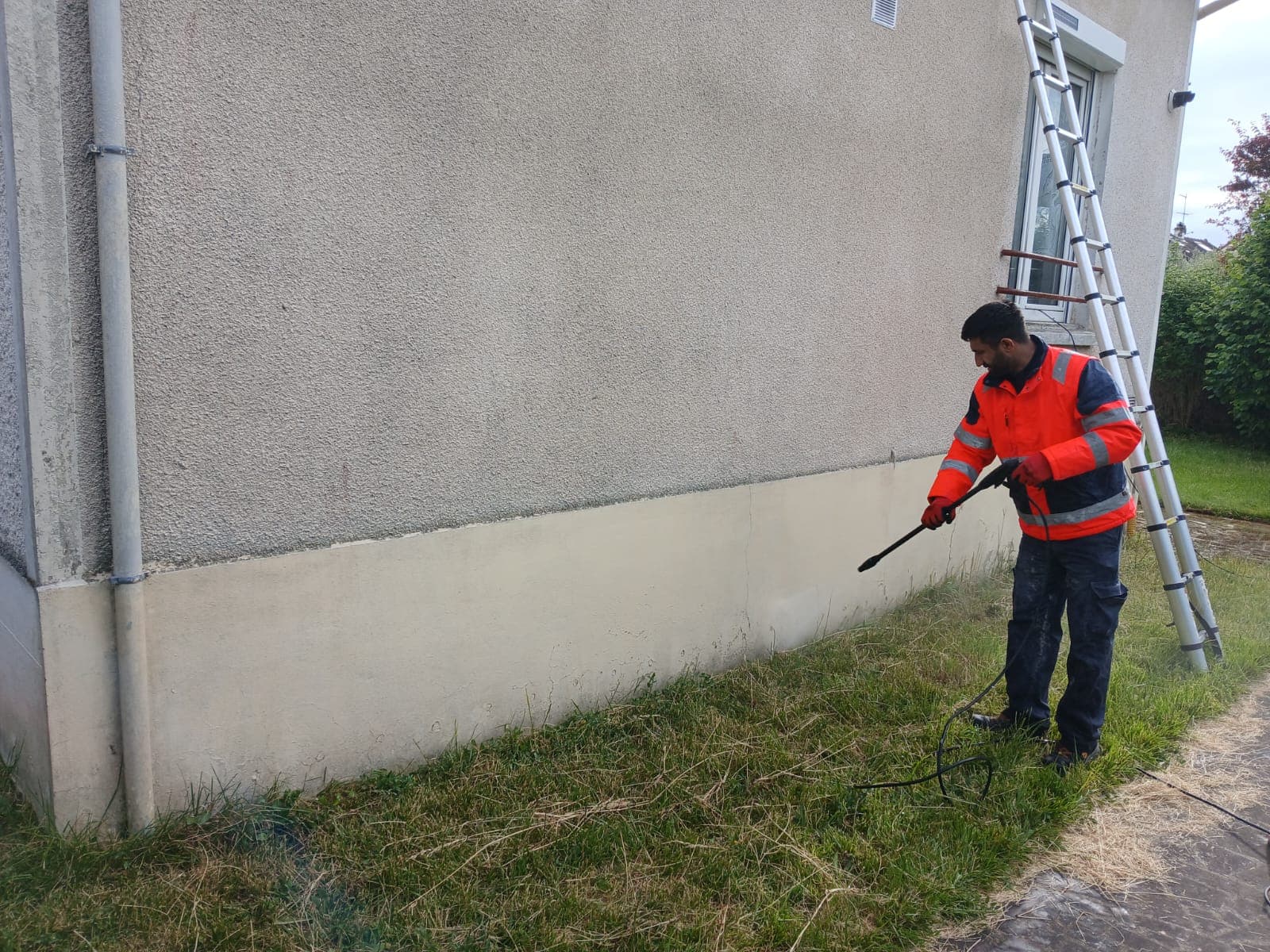 Ouvrier nettoyant la façade sur le sol